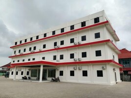 A multi-story building with a flat roof, several windows, and a covered entrance area.