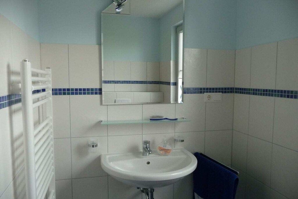 Une salle de bain avec un lavabo blanc, un miroir et un porte-serviettes.