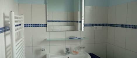 Une salle de bain avec un lavabo blanc, un miroir et un porte-serviettes.