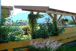 Ein Holzer Pergola-Gebilde in einem Garten mit Bergblick.