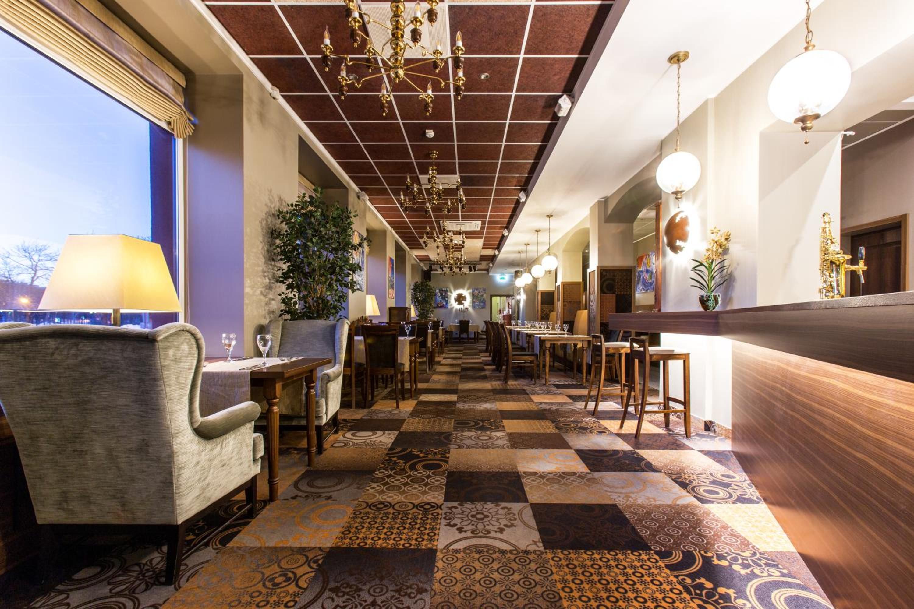 A hotel lobby with a check-in counter, seating area, and a patterned floor.