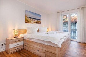 Ein Schlafzimmer mit einem hölzernen Bett, einem Nachttisch, einer Nachttischlampe und einem Fenster mit Vorhängen.