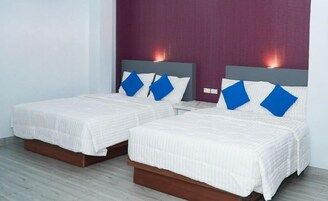 Two beds with headboards, white bedding, and blue pillows.