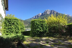 A garden with stone pathways, neatly trimmed bushes, and a mountain backdrop. - Holiday apartment in Telfes with sauna (Telfes)