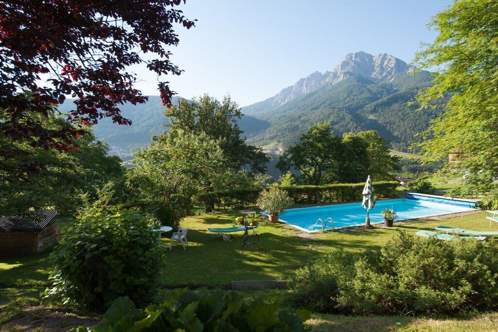 A pool surrounded by lush greenery and mountains in the background.