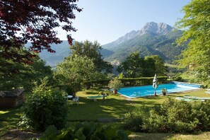 A pool surrounded by lush greenery and mountains in the background. - Holiday apartment in Telfes with sauna (Telfes)
