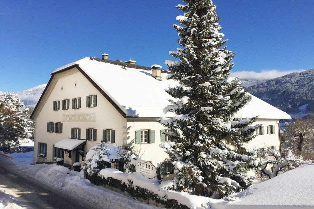 A snow-covered building with a sign that reads 'GRIEBER'S' and a snow-covered tree in front.