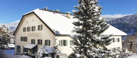 A snow-covered building with a sign that reads 'GRIEBER'S' and a snow-covered tree in front.