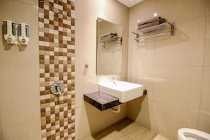 A bathroom with a sink, mirror, towel rack, and soap dispensers. - Akasia Budget Hotel (Promong)