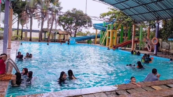 A swimming pool with multiple slides and a covered area. - Akasia Budget Hotel (Promong)