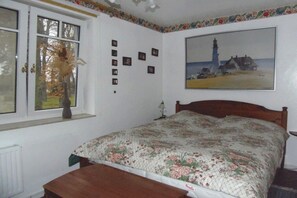 A bedroom with a bed, a window with a view, and a wall with framed pictures. - Holiday apartment with 2 bedrooms (Zinnowitz)