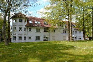 Ein mehrstöckiges Gebäude mit rotem Ziegeldach und weißen Wänden, das mehrere Fenster aufweist.