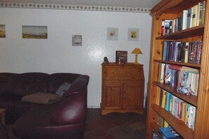 A living room with a leather sofa, a wooden cabinet, and a bookshelf filled with books. - Holiday apartment with 2 bedrooms (Zinnowitz)