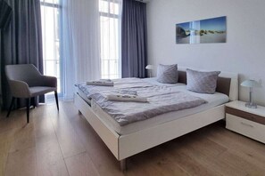A modern bedroom with a bed, a chair, a nightstand, and a painting on the wall. - Holiday apartment with 2 bedrooms (Sellin)