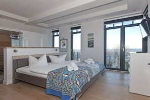 A modern bedroom with a large bed, a wardrobe, and a balcony with a view. - Holiday apartment with 2 bedrooms (Sellin)