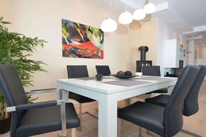 Ein stilvoller Essbereich mit einem weißen Tisch, schwarzen Stühlen, einem Bild an der Wand und einem Blumentopf.