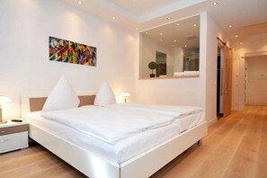 Ein modernes Schlafzimmer mit einem großen Bett, Nachttischen, einem Spiegel und einem farbenfrohen abstrakten Gemälde an der Wand.