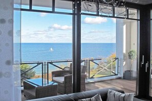 A balcony with a view of the sea, wicker furniture, and a glass door. - Holiday apartment with 2 bedrooms (Sellin)
