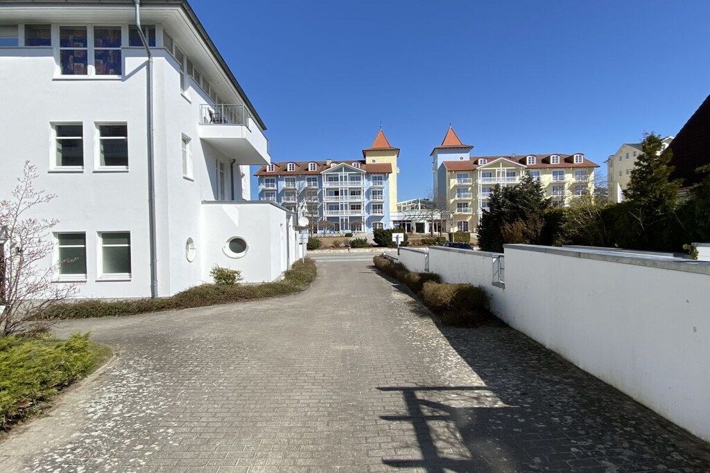 A paved pathway leading to a building with a white facade and multiple windows.