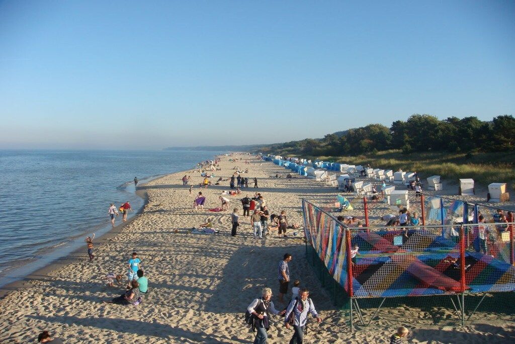 A beach with people, tents, and a fenced play area.