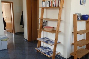 A hallway with a wooden bookshelf, a basket, and a blue object on a shelf. - Holiday apartment with 1 bedroom (Zinnowitz)