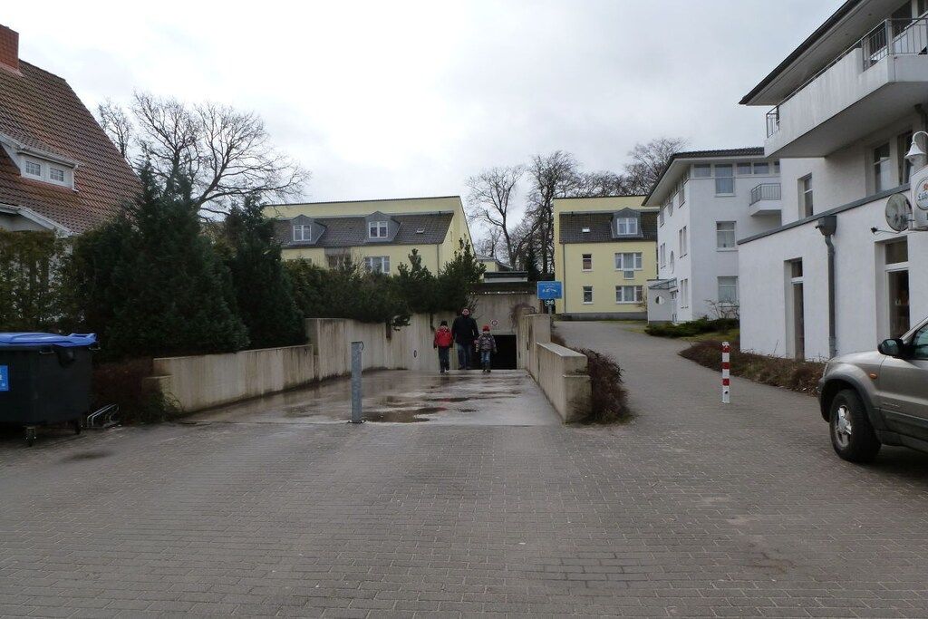 Eine Wohnstraße mit Häusern, einem gepflasterten Gehweg und einem parkenden Auto.