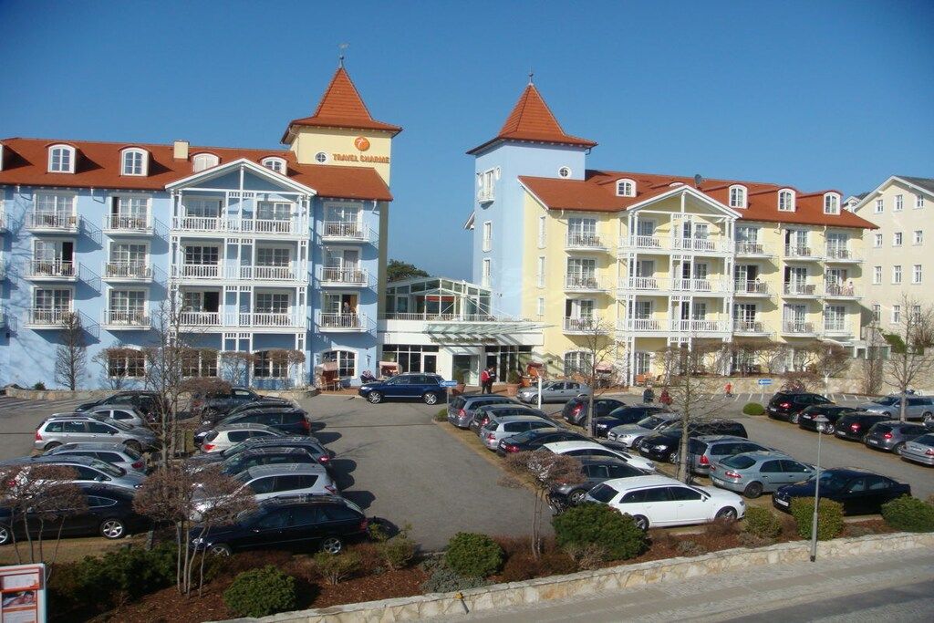 Ein mehrstöckiges Hotel mit Balkonen, einem Parkplatz und blauem Himmel.