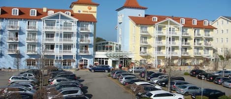 Ein mehrstöckiges Hotel mit Balkonen, einem Parkplatz und blauem Himmel.