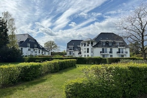 A large, multi-story residential building with a symmetrical facade, surrounded by well-maintained hedges and a manicured lawn. - 46 Residence at Balmer Lake (Benz)
