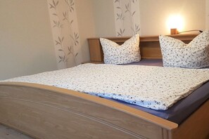 Ein Bett mit hölzernem Kopfteil, einer blumigen Tagesdecke und passenden Kissen.