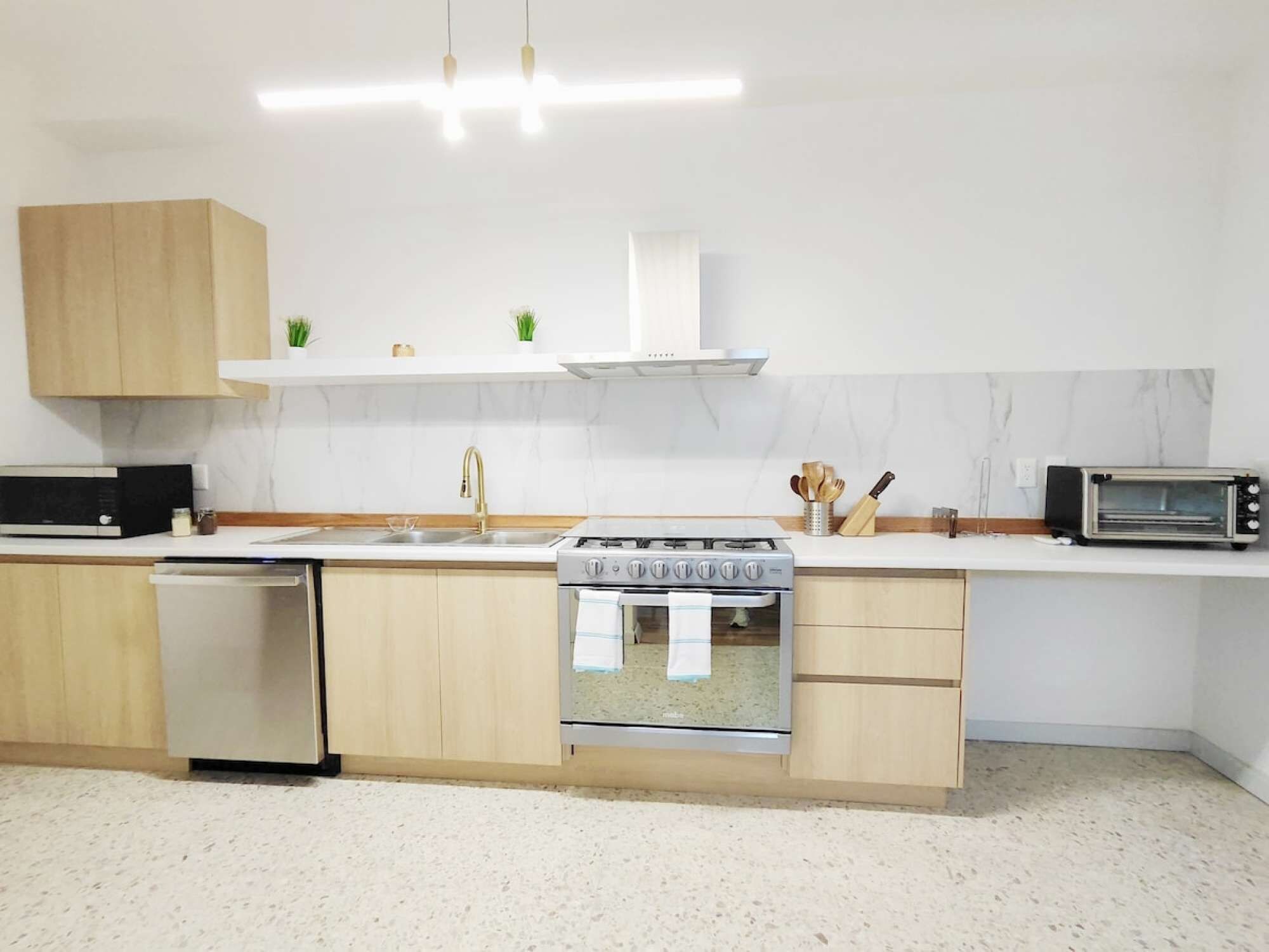 Eine moderne Küche mit Geschirrspüler, Herd, Mikrowelle und Holzschränken.