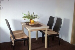 A dining area with a table and four chairs, a small plant on the table, and a carpeted floor. - Bauer 2 Mountain View (Thale)