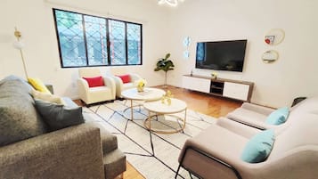 A modern living room with a sofa set, a coffee table, a TV, and a large window with a view.