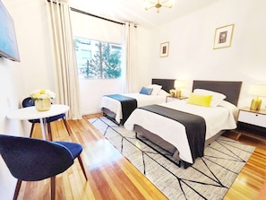 A hotel room with two beds, a small table, a chair, and a view of the outdoors. - Laila Casa + Luz María 5 · Polanco, sleeps 15 · 5.5 baths (Ciudad de México)