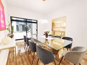 A modern dining area with a glass table, grey upholstered chairs, and a vase with flowers. - Laila Casa + Luz María 5 · Polanco, sleeps 15 · 5.5 baths (Ciudad de México)