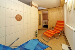 Ein Badezimmer mit einer gefliesten Wand, einer Holztür, einem blauen Handtuch und einem gestreiften Handtuch.