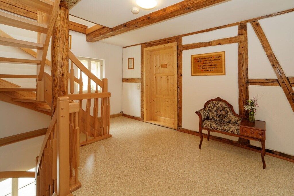 Un escalier en bois mène à une pièce qui contient une porte, un banc et une plaque fixée au mur.
