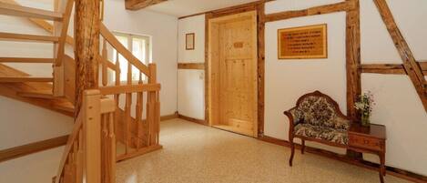 A wooden staircase leading to a room with a door, a bench, and a plaque on the wall.