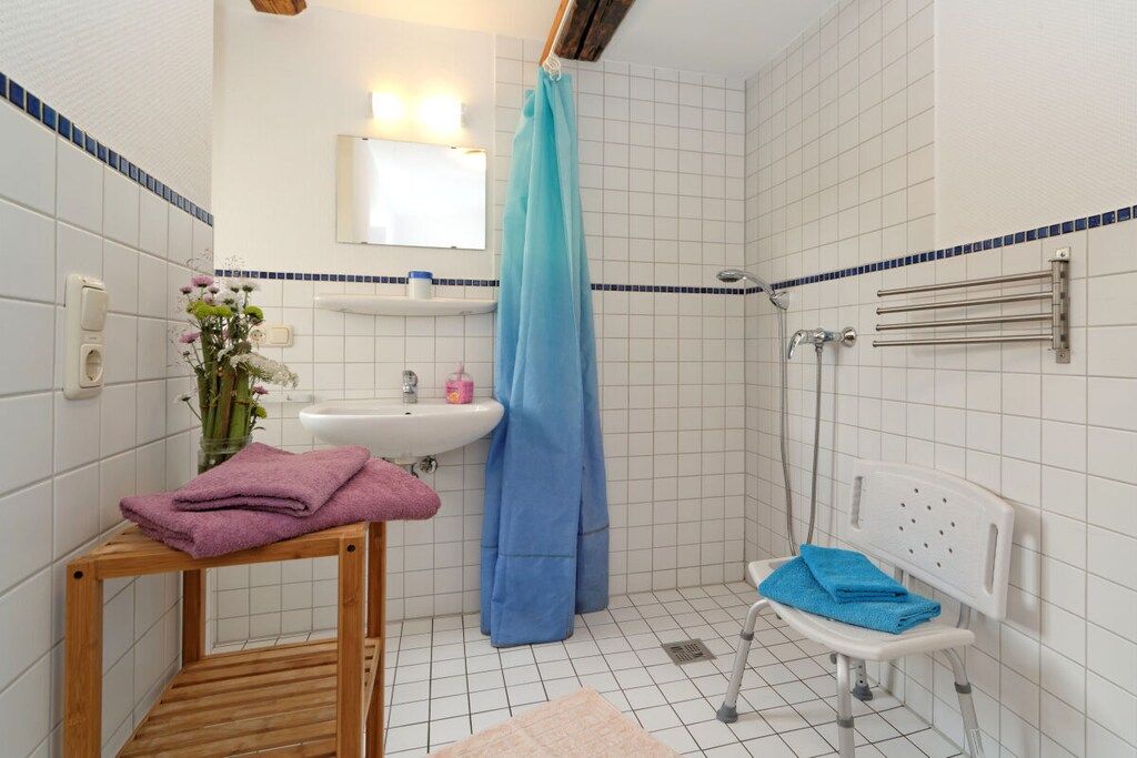 Ein Badezimmer mit Dusche, Waschbecken und einer Sitzbank.