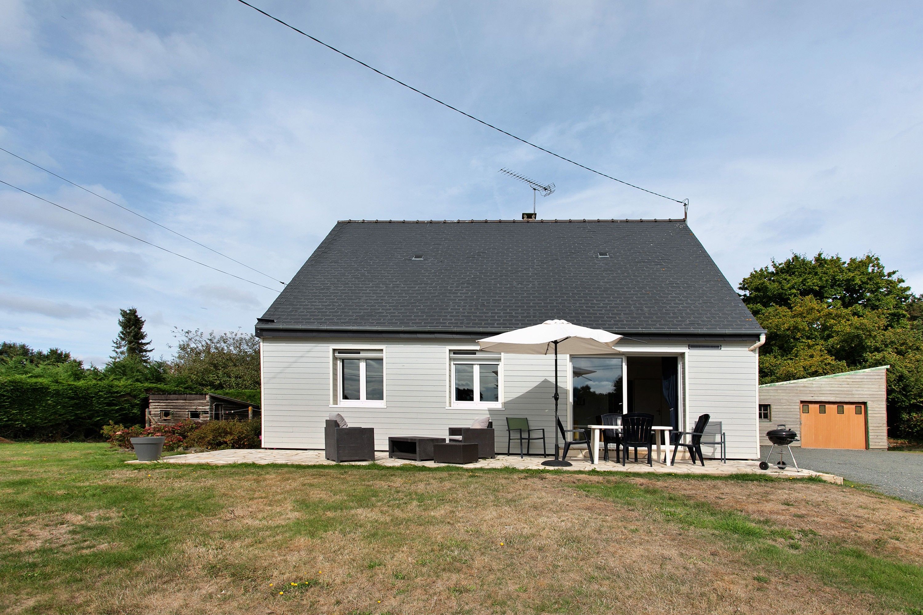 Een huis met twee verdiepingen, een terras, een garage en een kleine tuin.