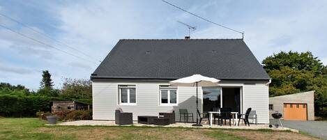 Een huis met twee verdiepingen, een terras, een garage en een kleine tuin.