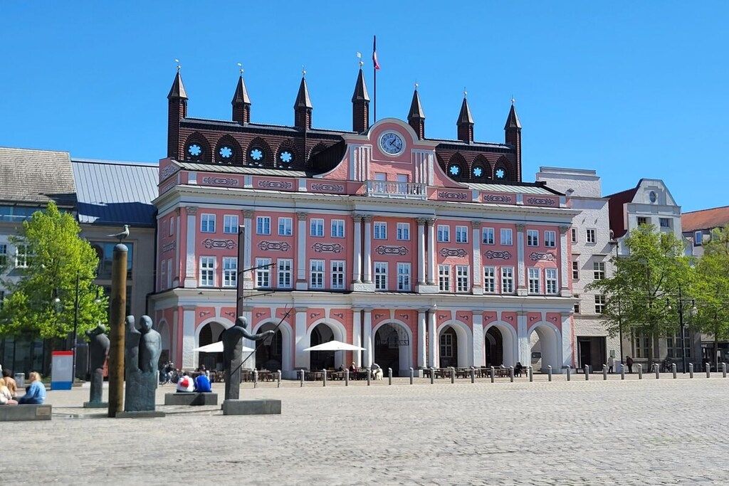 Un edificio histórico con una torre de reloj, ventanas arqueadas y una entrada central.