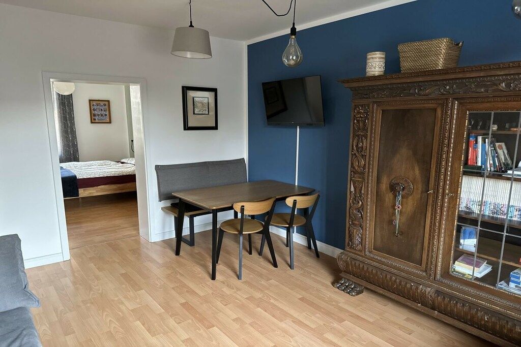 Een kamer met een eettafel, stoelen, een televisie en een kast met boeken.