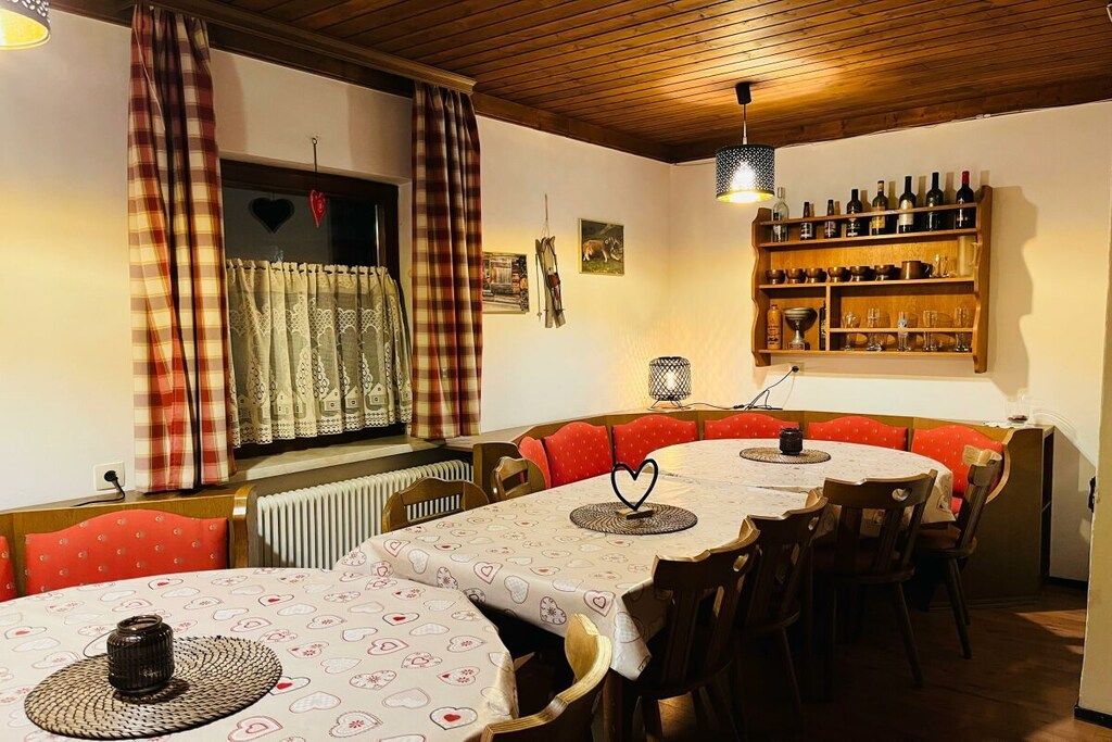 A dining area with a round table, red cushioned chairs, a wine rack, and a radiator.