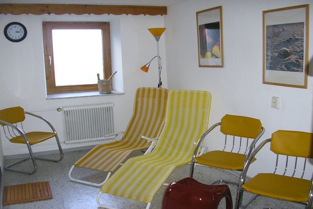 Une pièce comprenant deux fauteuils à rayures, un radiateur, une fenêtre, une horloge et une lampe.
