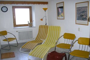 Ein Zimmer mit zwei gestreiften Lounge-Sesseln, einem Heizkörper, einem Fenster, einer Uhr und einer Lampe.
