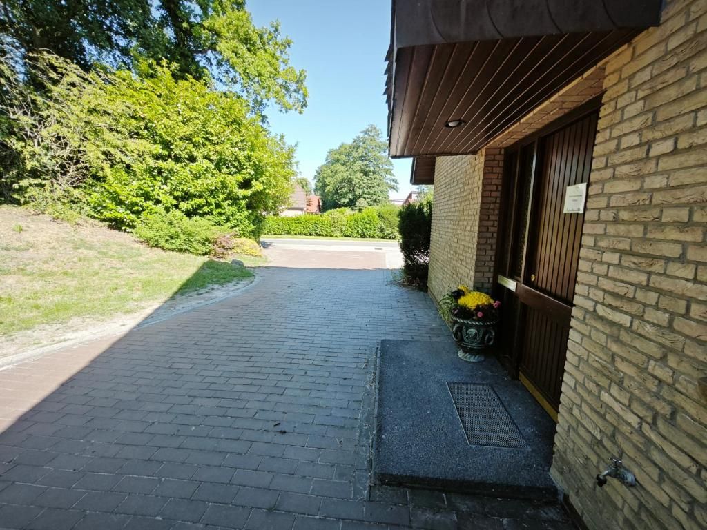 A paved pathway leading to a building with a brick facade and a wooden door.