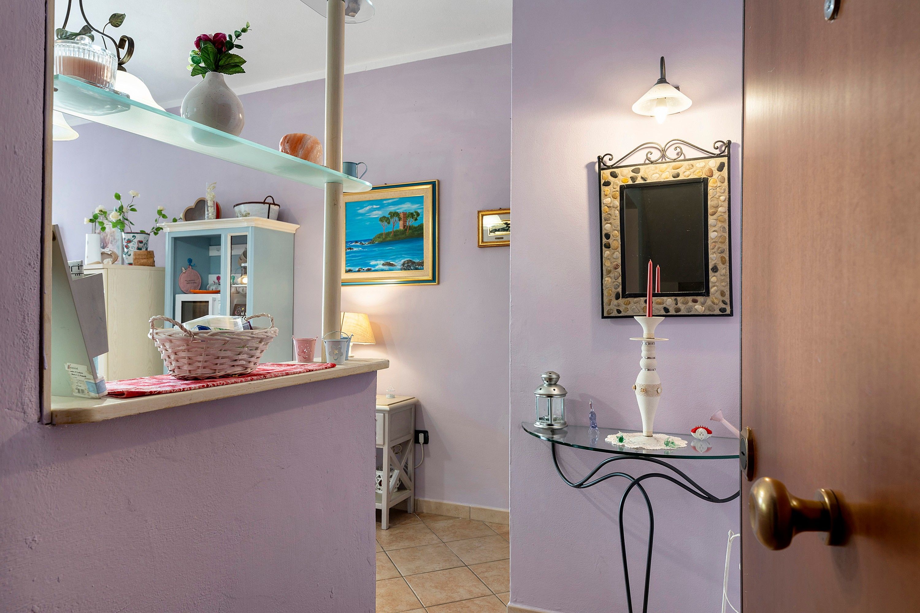 A bathroom with a vanity, a mirror, a framed painting, and a decorative vase.