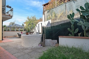 A courtyard with a cactus, a table with chairs, and a building with a balcony. - Holiday Home 'La Casa di Monica' with Private Garden and Wi-Fi (Pescia)