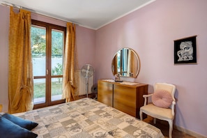 Un dormitorio con cama, cómoda, silla, espejo y ventana con cortinas.